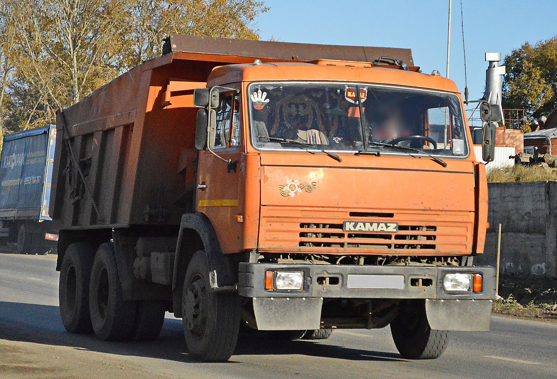 Оранжевый самосвал КАМАЗ-65115 грузоподъемностью 15 тонн на стоянке