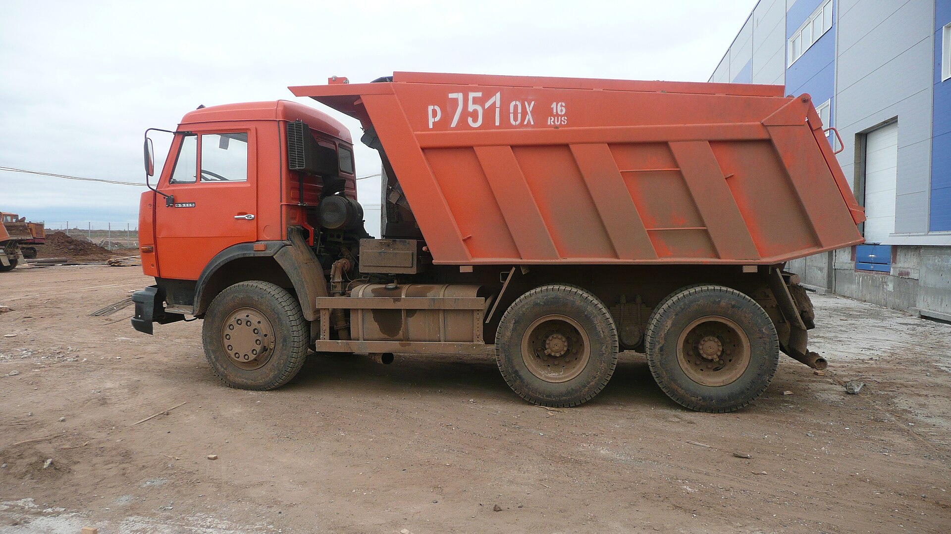 Красно-оранжевый самосвал КАМАЗ-65115, вид сбоку